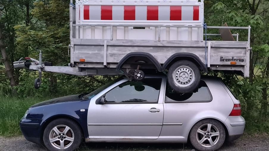 Das beschädigte Auto samt Anhänger: Wie ist er auf das Dach gekommen?