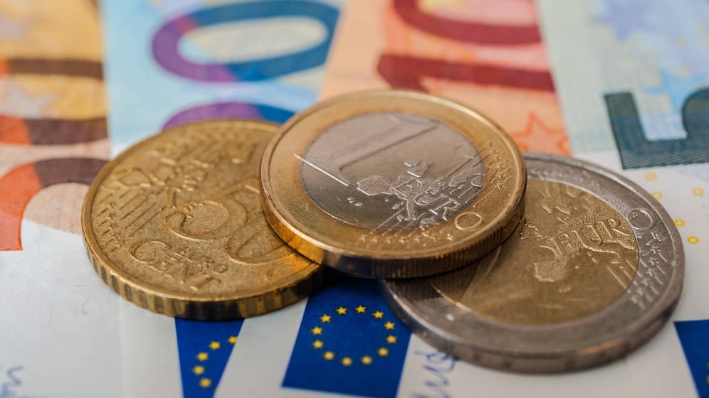 Euromünzen auf Geldscheinen (Symbolbild): Wer eine Riester-Rentenversicherung besitzt, bekommt in diesen Tagen Post.