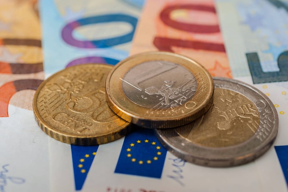 Euromünzen auf Geldscheinen (Symbolbild): Wer eine Riester-Rentenversicherung besitzt, bekommt in diesen Tagen Post.