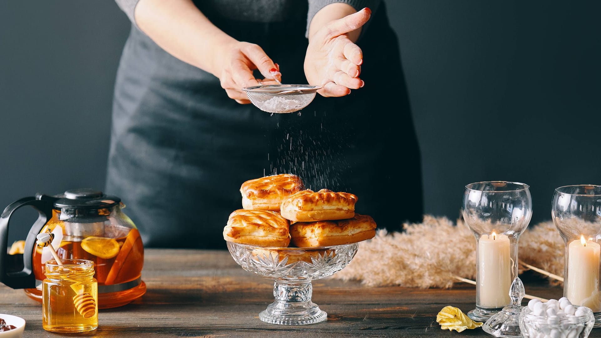 Die Arbeit eines Food Stylisten: Frau streut Puderzucker über Backwaren, um sie perfekt für ein Photoshooting zu arrangieren.