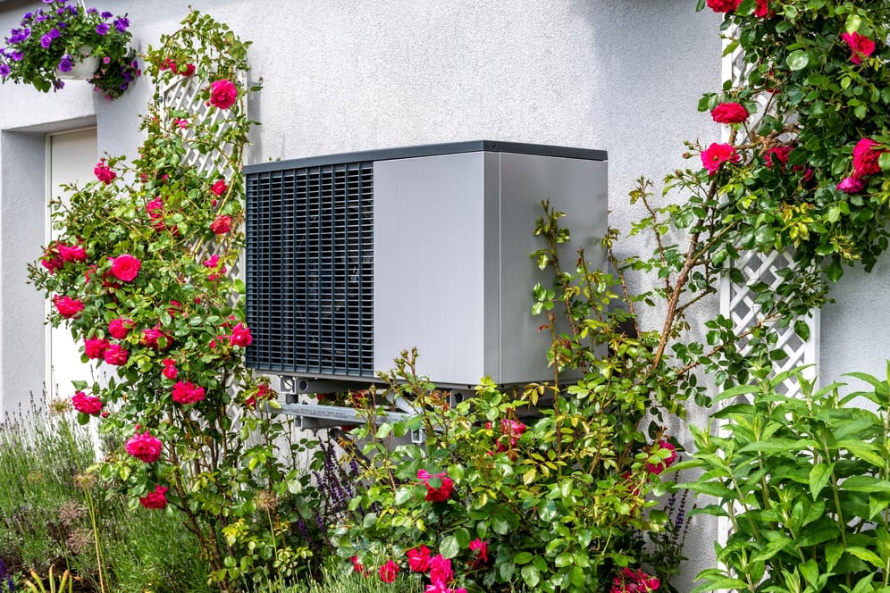 Wärmepumpe an der Außenwand eines Hauses (Symbolbild): Die Geräte brauchen selbst Strom – und der sollte am besten möglichst günstig sein.