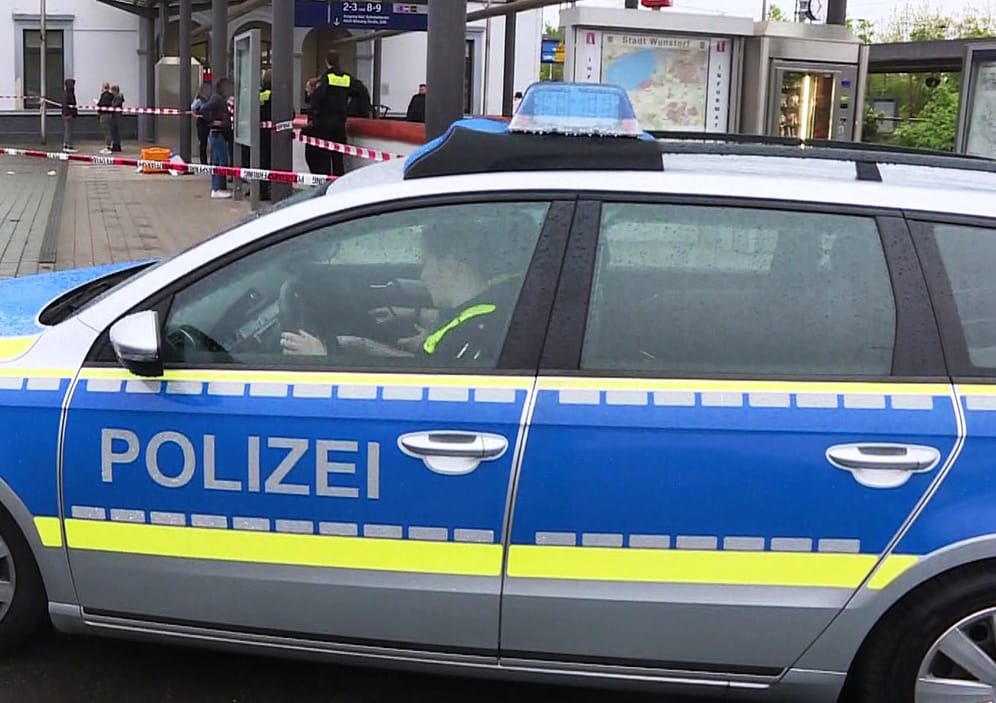 Polizisten sitzen in einem Polizeiauto am Bahnhof in Wunstorf: Hier ist es am Freitag zu einer Messerattacke gekommen.