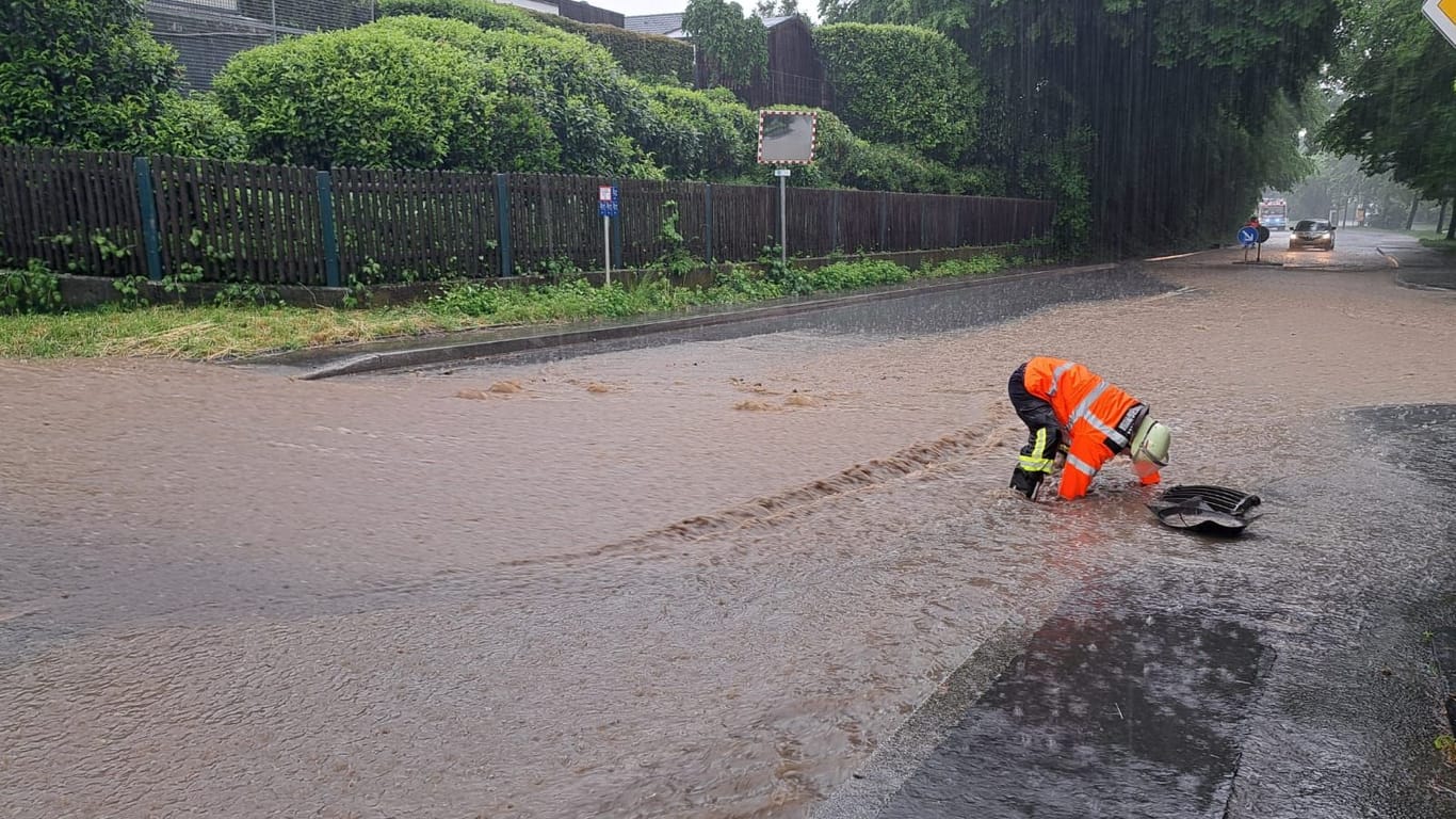 Überschwemmungen in Fröndenberg: Ein Feuerwehrmann auf einer überfluteten Straße in Fröndenberg.