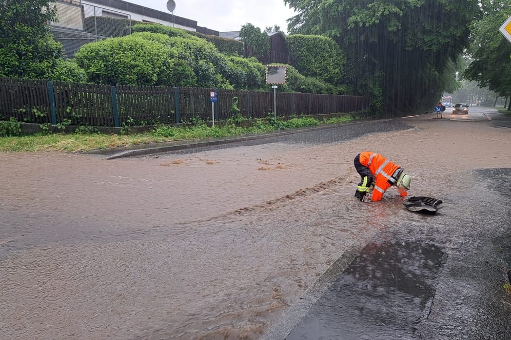 Überschwemmungen in Fröndenberg: Ein Feuerwehrmann auf einer überfluteten Straße in Fröndenberg.