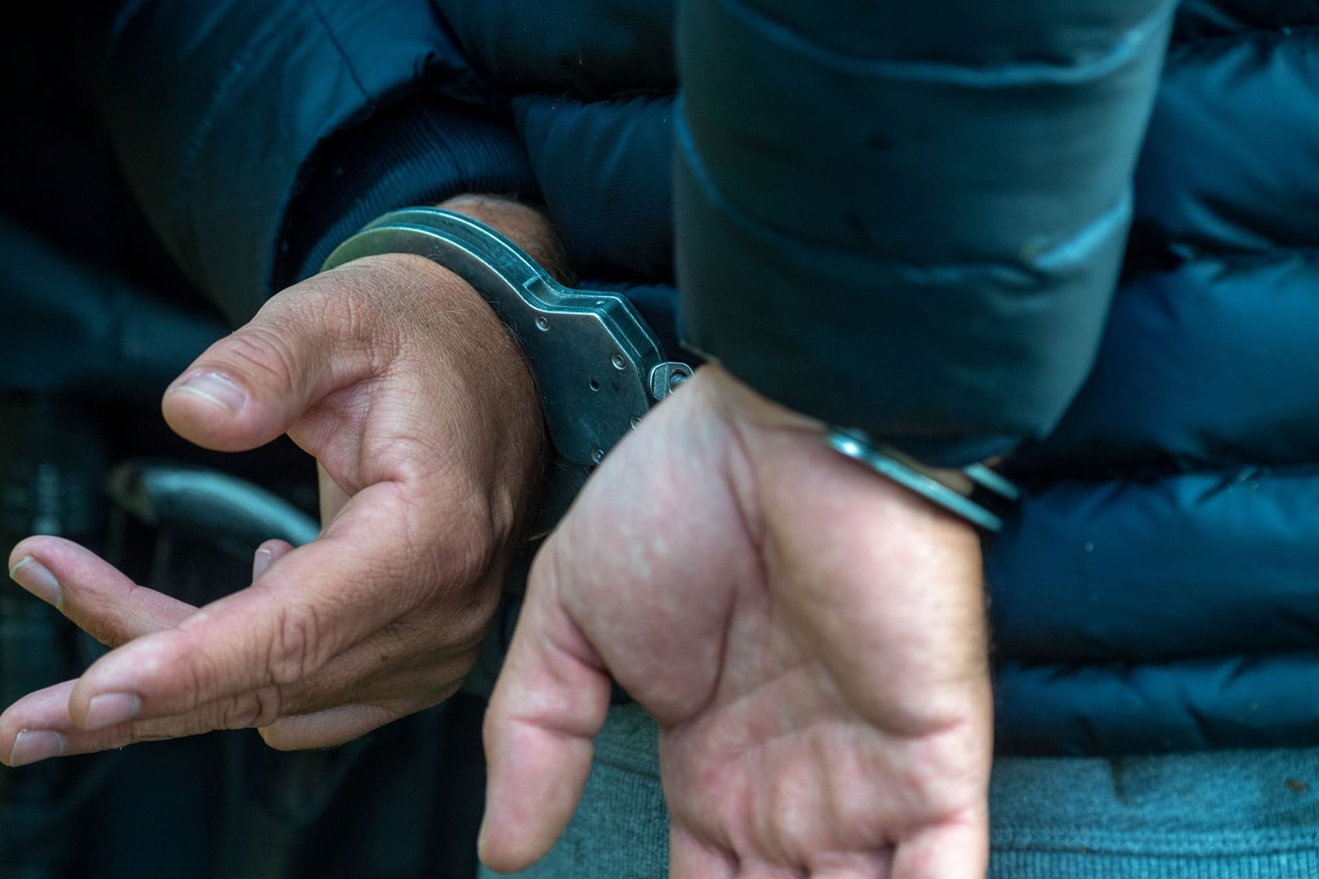 Ein Mann trägt Handschellen (Symbolbild): Nachdem der 33-Jährige erst die Kinder anging, dann deren Eltern beleidigte, griff er auch noch die Polizisten an.