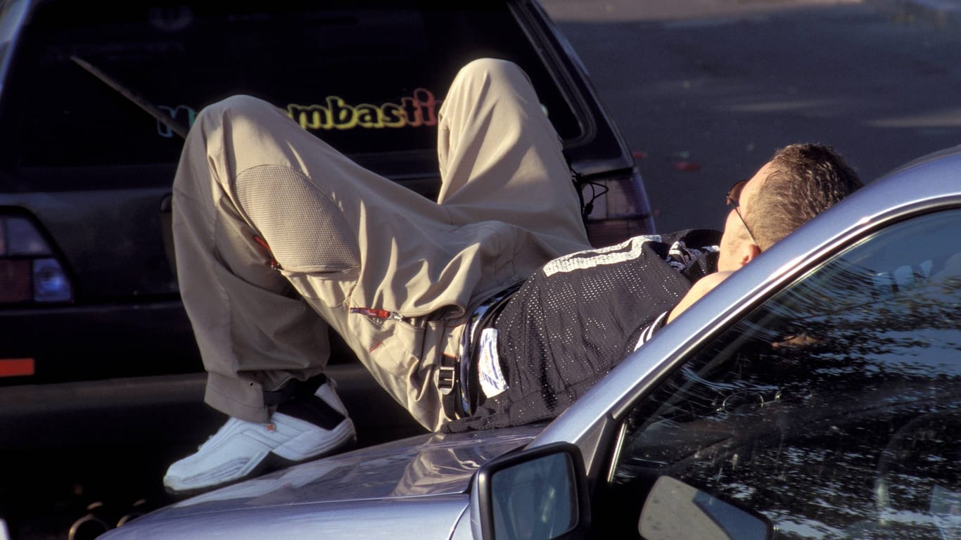 Ein Mann schläft auf einer Motorhaube (Symbolfoto): Gegen den 20-Jährigen wird ermittelt.