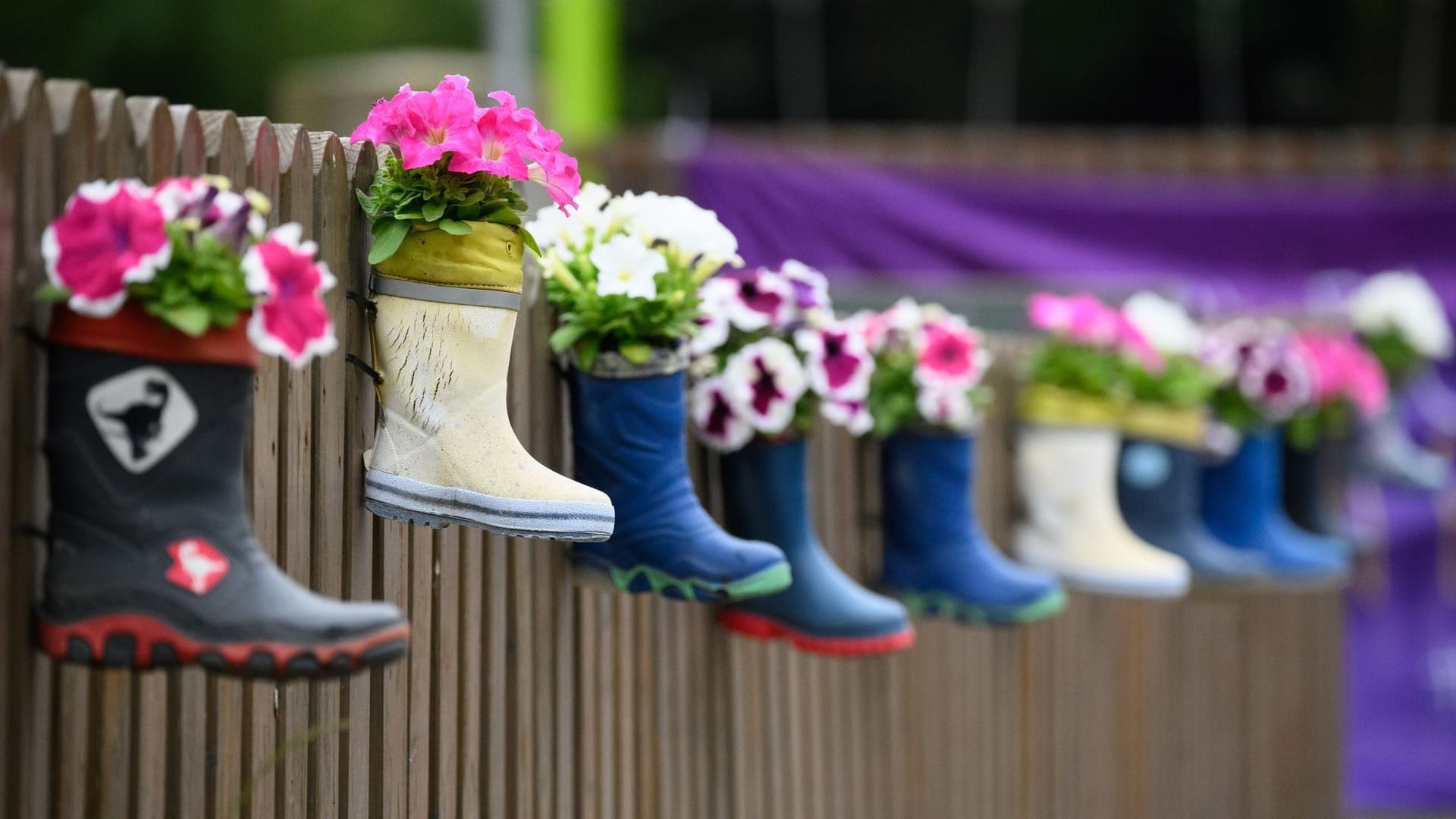 Kinder-Gummistiefel mit Blumen hängen an einem Zaun einer Kindertagesstätte (Symbolbild): Bei einer Fachkonferenz in Hannover wurde über den Personalmangel in Kitas gesprochen.