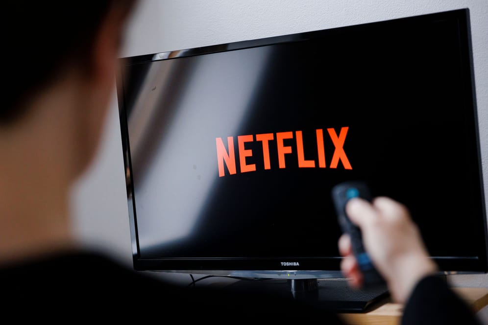 Ein Mann startet Netflix auf seinem Fernseher: Aktuell versuchen Betrüger mit angeblichen Mails von Netflix an Daten zu gelangen.