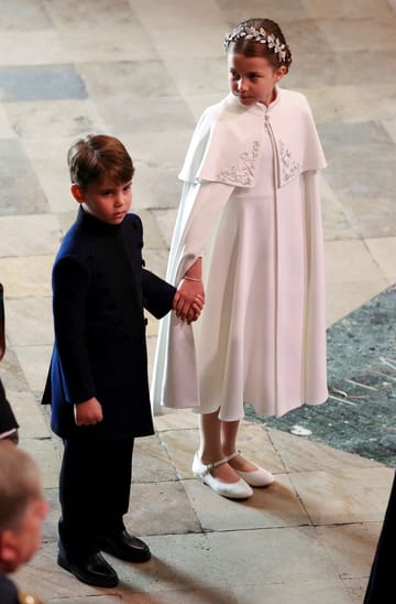 Prince Louis and Princess Charlotte hold hands.