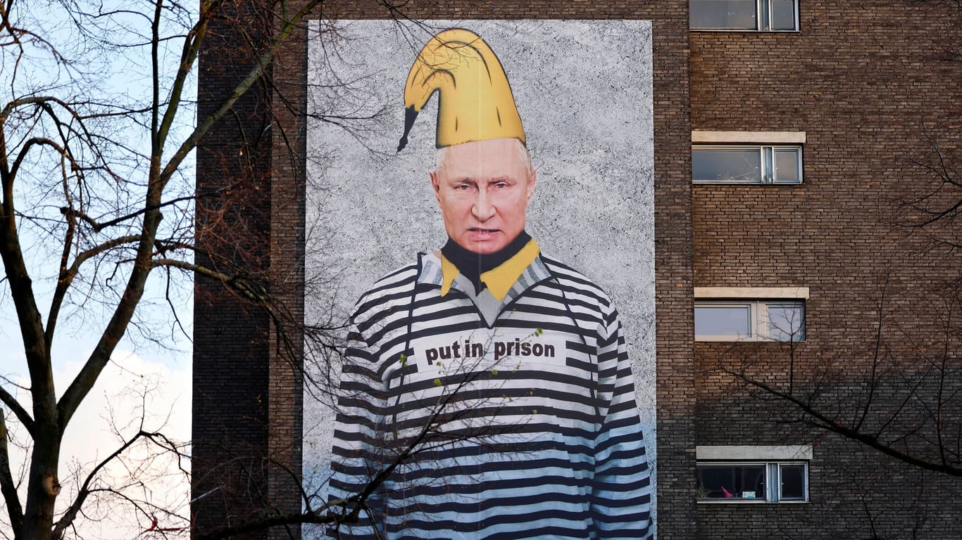 Der russische Präsident Wladimir Putin ist auf einem XXL-Banner in Sträflingskleidung zu sehen: Hinter der Aktion steht der Kölner Bananen-Künstler Thomas Baumgärtel.