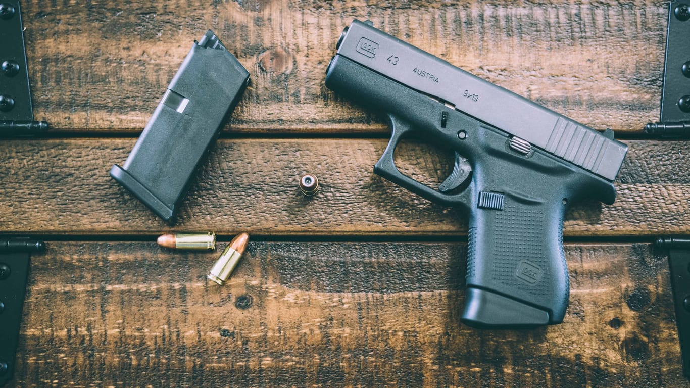 Munition und Waffe liegen auf einem Tisch (Symbolbild). Als der Mann die Jugendlichen auf seinem Grundstück weglaufen sah, habe er geschossen.