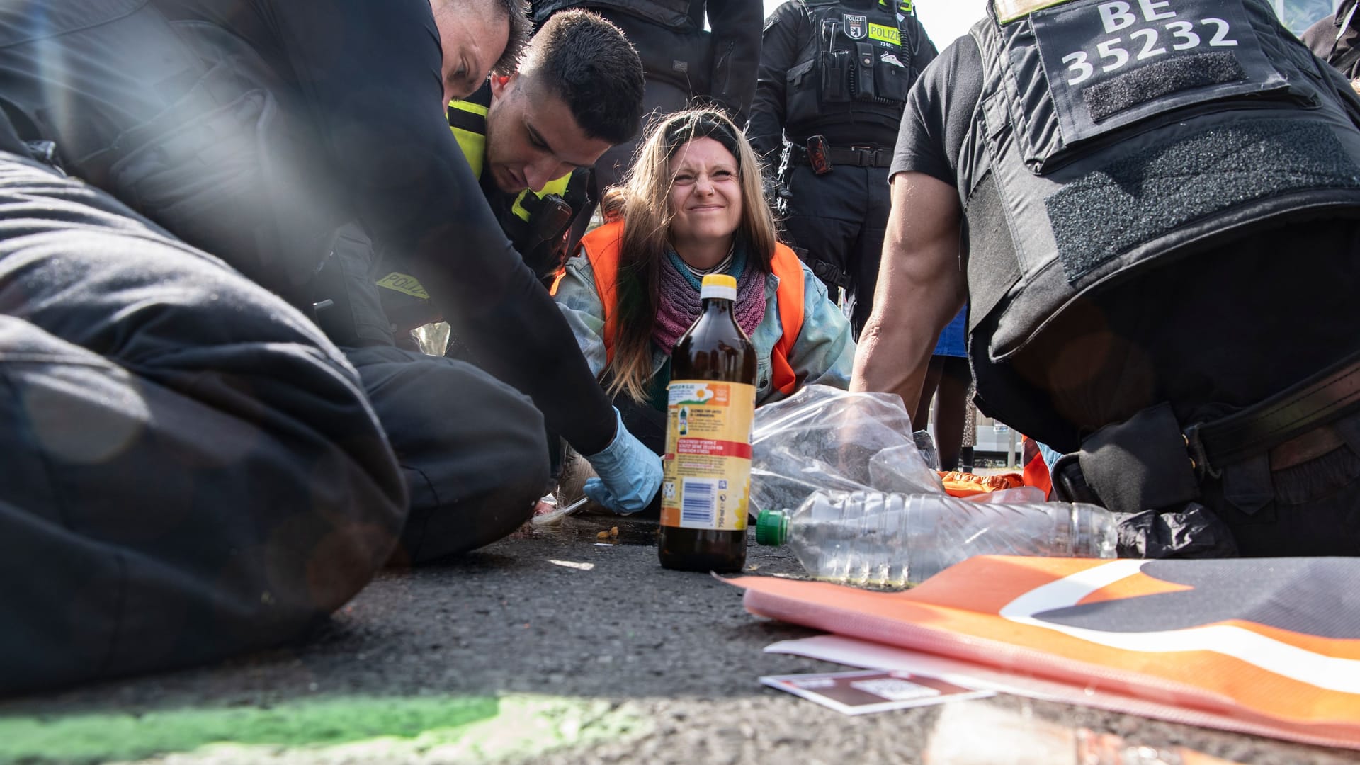 Polizisten lösen die Hand einer Aktivistin der "Letzten Generation" vom Asphalt des Ernst-Reuter-Platzes in Berlin.