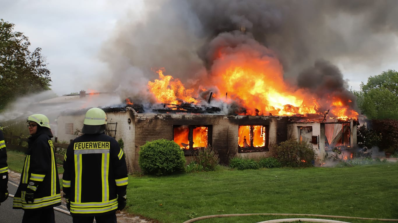 Einsatzkräfte stehen vor dem brennenden Haus: Der Sachschaden liegt im mittleren sechsstelligen Bereich.