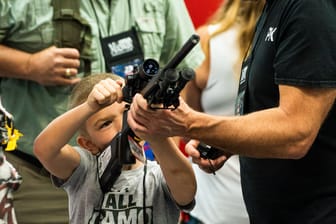 Waffenmesse in Indianapolis im April 2023: Ein Aussteller zeigt einem kleinen Jungen, wie ein Sturmgewehr funktioniert.