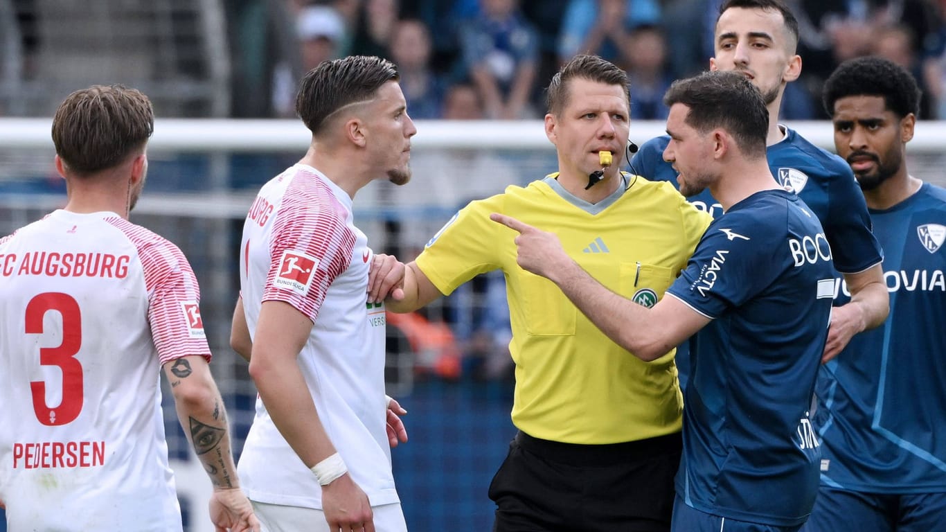 Schiedsrichter Patrick Ittrich (Mitte) schlichtet einen Streit zwischen Kevin Stöger (r.) und Ermedin Demirovic (l.): Der FC Augsburg kassierte in dieser Saison die meisten Gelben Karten.