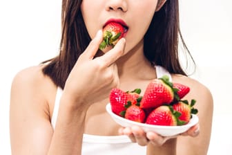 Frau isst Erdbeeren: Wenn die Frucht auf einem weißen Shirt landet, muss schnell gehandelt werden.