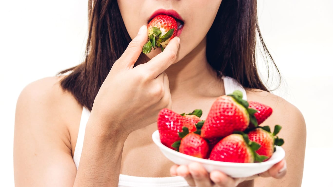 Frau isst Erdbeeren: Wenn die Frucht auf einem weißen Shirt landet, muss schnell gehandelt werden.
