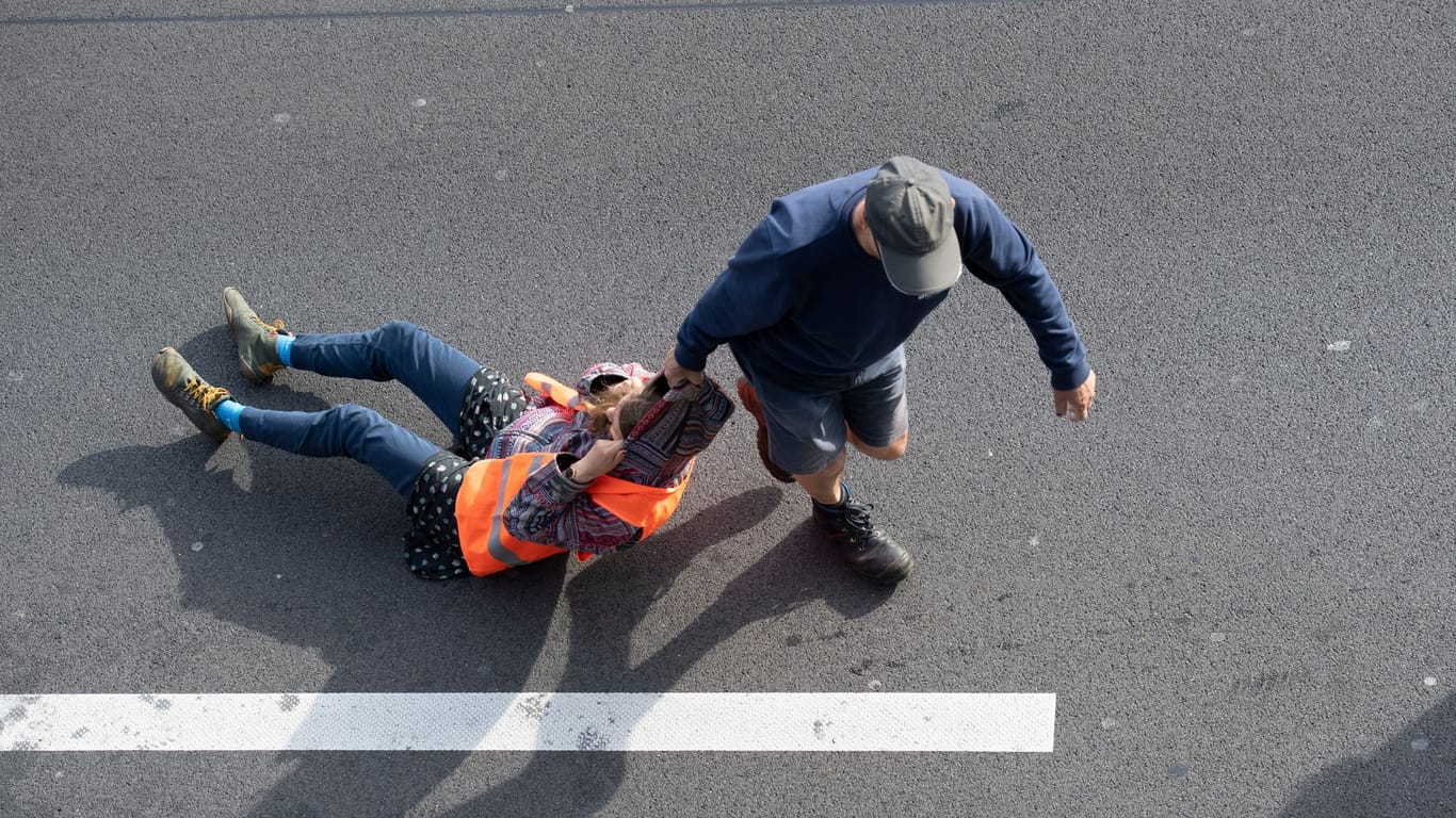 Ein Verkehrsteilnehmer (r) zieht eine Aktivistin von der Straße (Archivbild): Immer wieder gibt es Streit zwischen Aktivisten und Verkehrsteilnehmer.