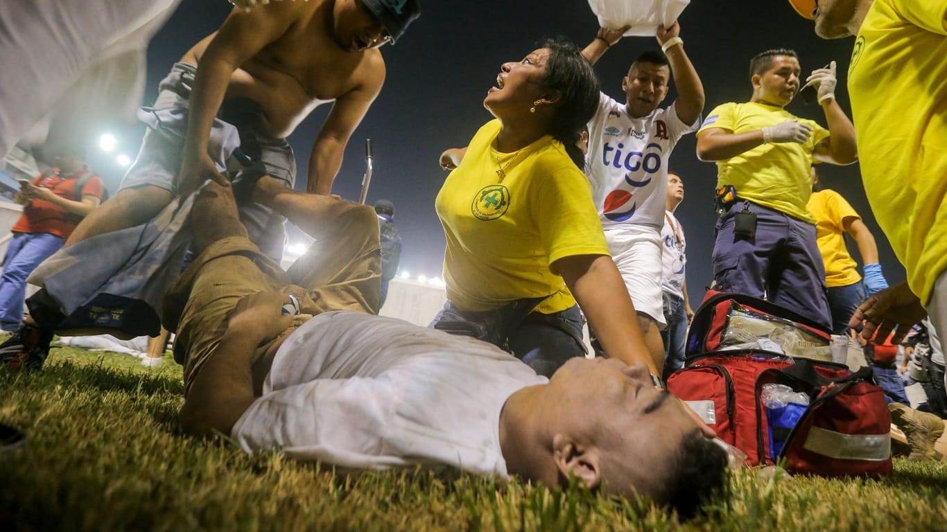 Rettungskräfte kümmern sich um einen verletzten Fan: Bei einer Massenpanik in El Salvador kamen mehrere Menschen ums Leben.