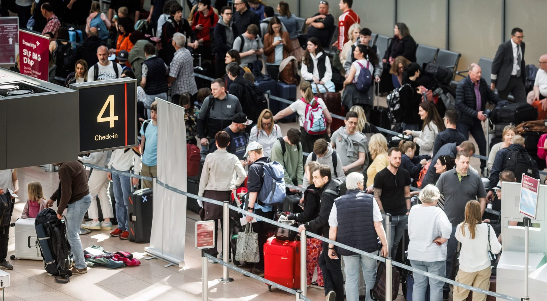Menschen stehen im Flughafen vor dem Security-Check in einer langen Schlange.