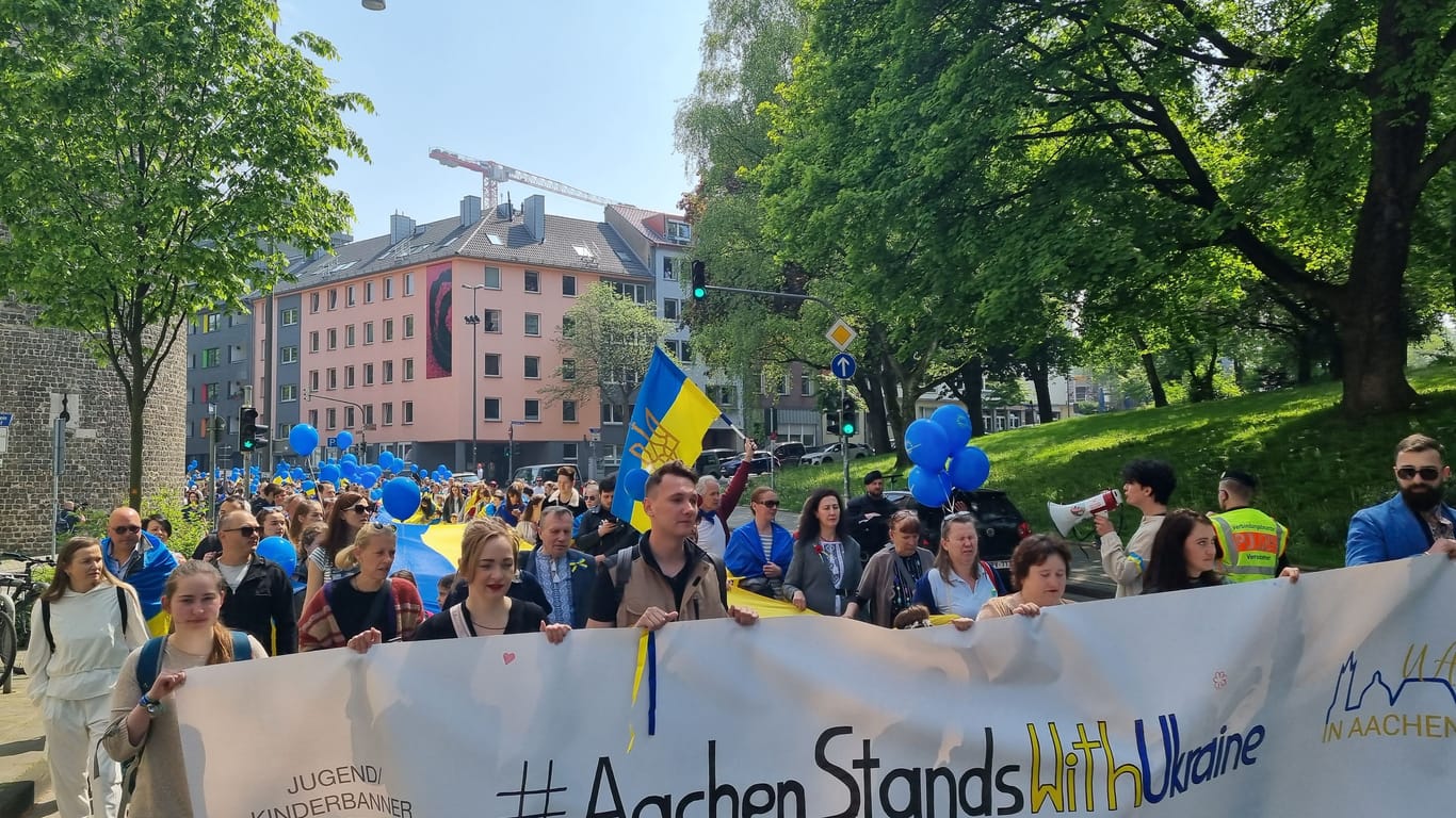Die Demo "Aachen stands with Ukraine": Hunderte Demonstrierende positionieren sich mit blauen Luftballons und einer meterlangen Fahne für die Ukraine.