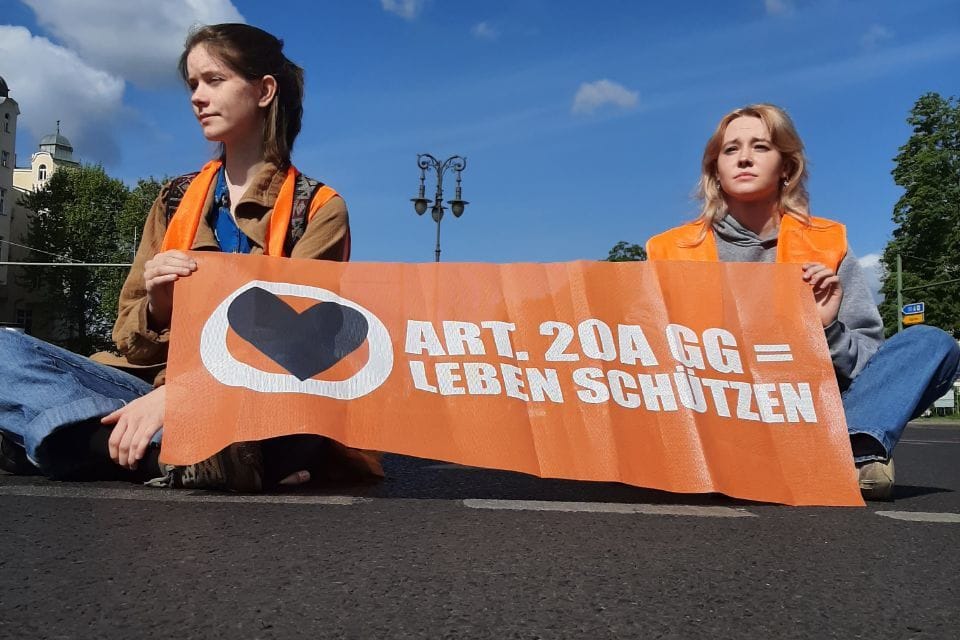 Zwei junge Frauen sitzen auf einer Straße: In Berlin blockieren Klimaaktivisten erneut die Straßen. Zwei junge Frauen sitzen auf einer Straße: In Berlin blockieren Klimaaktivisten erneut die Straßen.