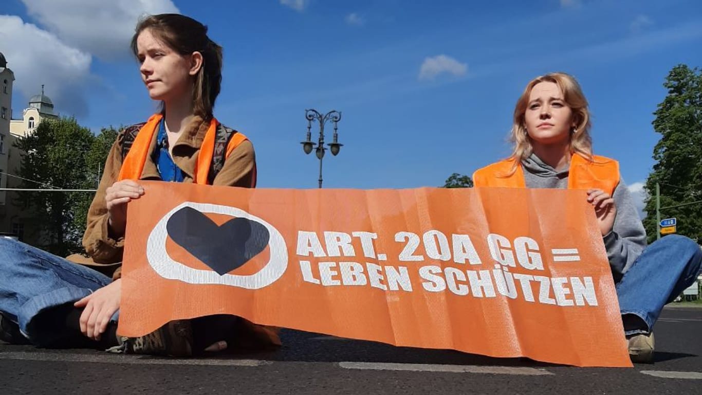 Zwei junge Frauen sitzen auf einer Straße: In Berlin blockieren Klimaaktivisten erneut die Straßen.