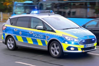 Ein Polizeiauto fährt mit Blaulicht durch eine Straße zu einem Einsatz (Symbolbild): Die Polizei in Köln ermittelt in einem Fall von Fahrerflucht.