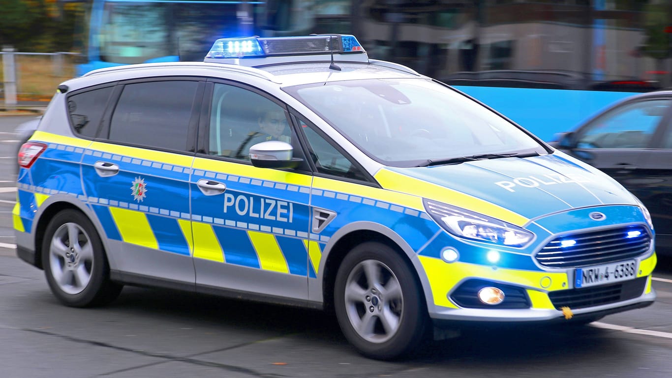 Ein Polizeiauto fährt mit Blaulicht durch eine Straße zu einem Einsatz (Symbolbild): Die Polizei in Köln ermittelt in einem Fall von Fahrerflucht.
