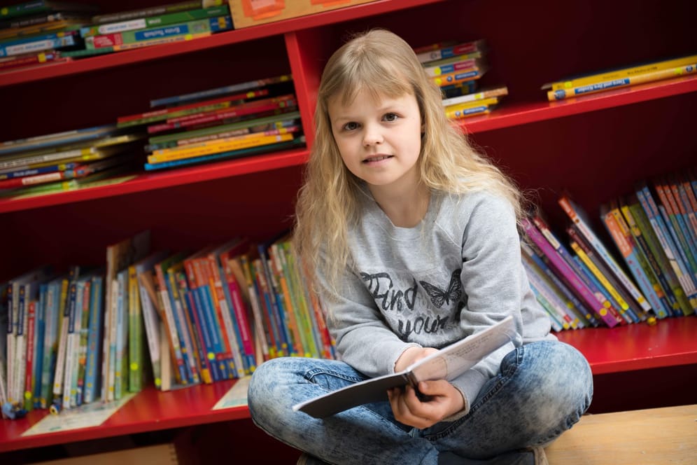 Antastasia Savenko sitzt mit einem Buch in plattdeutscher Sprache in ihrer Schule. Die Neunjährige ist vor einem Jahr mit ihrer Familie aus der Ukraine nach Deutschland geflüchtet.