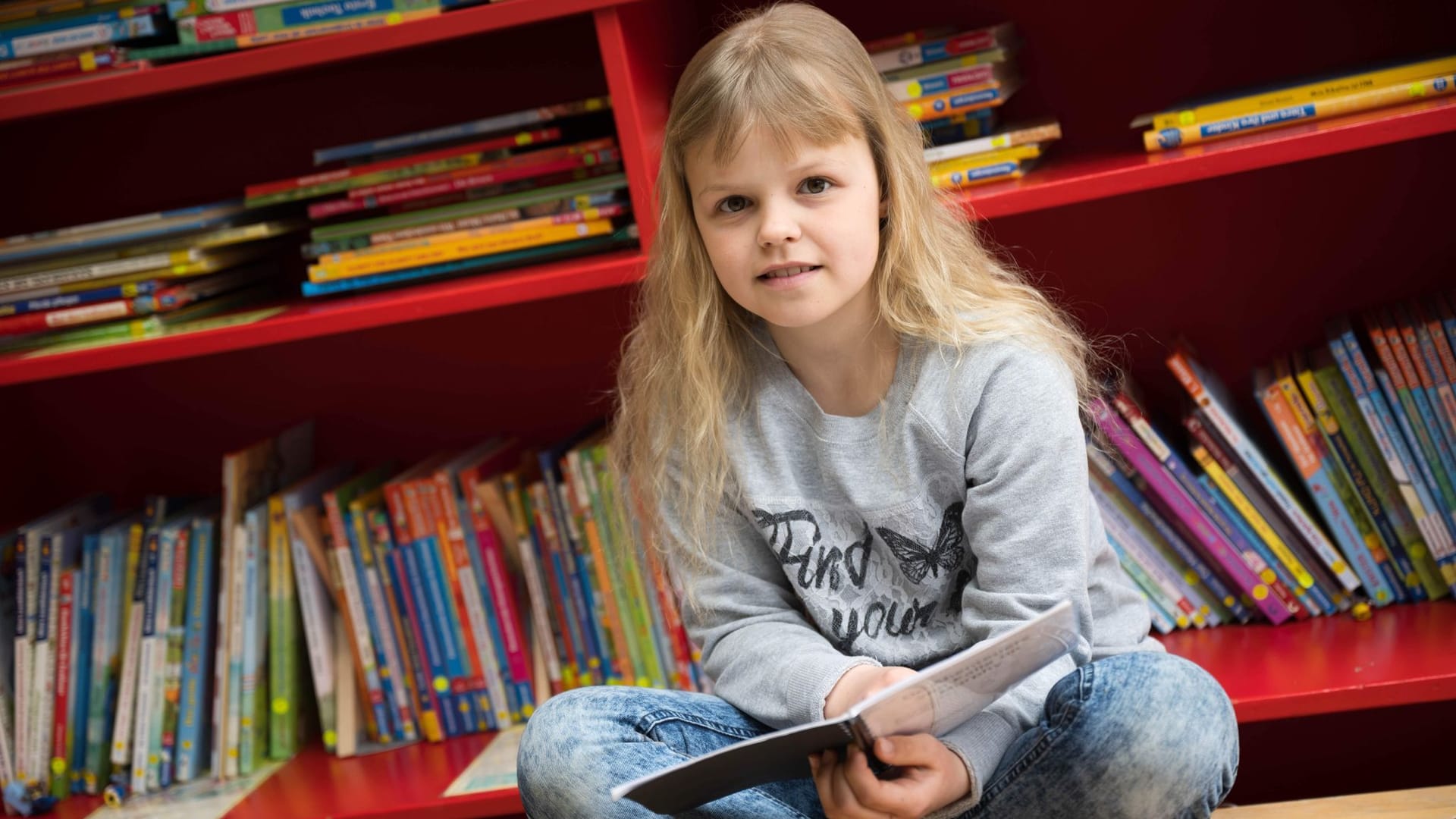 Antastasia Savenko sitzt mit einem Buch in plattdeutscher Sprache in ihrer Schule. Die Neunjährige ist vor einem Jahr mit ihrer Familie aus der Ukraine nach Deutschland geflüchtet.