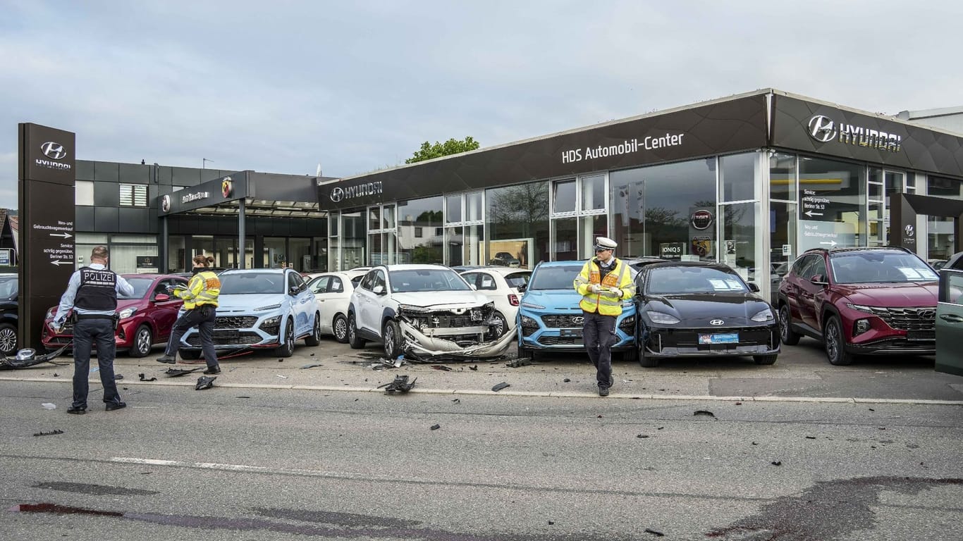 Polizeibeamte nehmen vor einen Autohaus einen Schaden auf: In Leonberg raste ein Auto in mehrere Neuwagen.