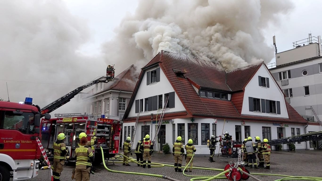 Die Einsatzkräfte der Feuerwehr sind bei den Löscharbeiten an einem Mehrfamilienhaus in der Innenstadt Achims (Landkreis Verden).