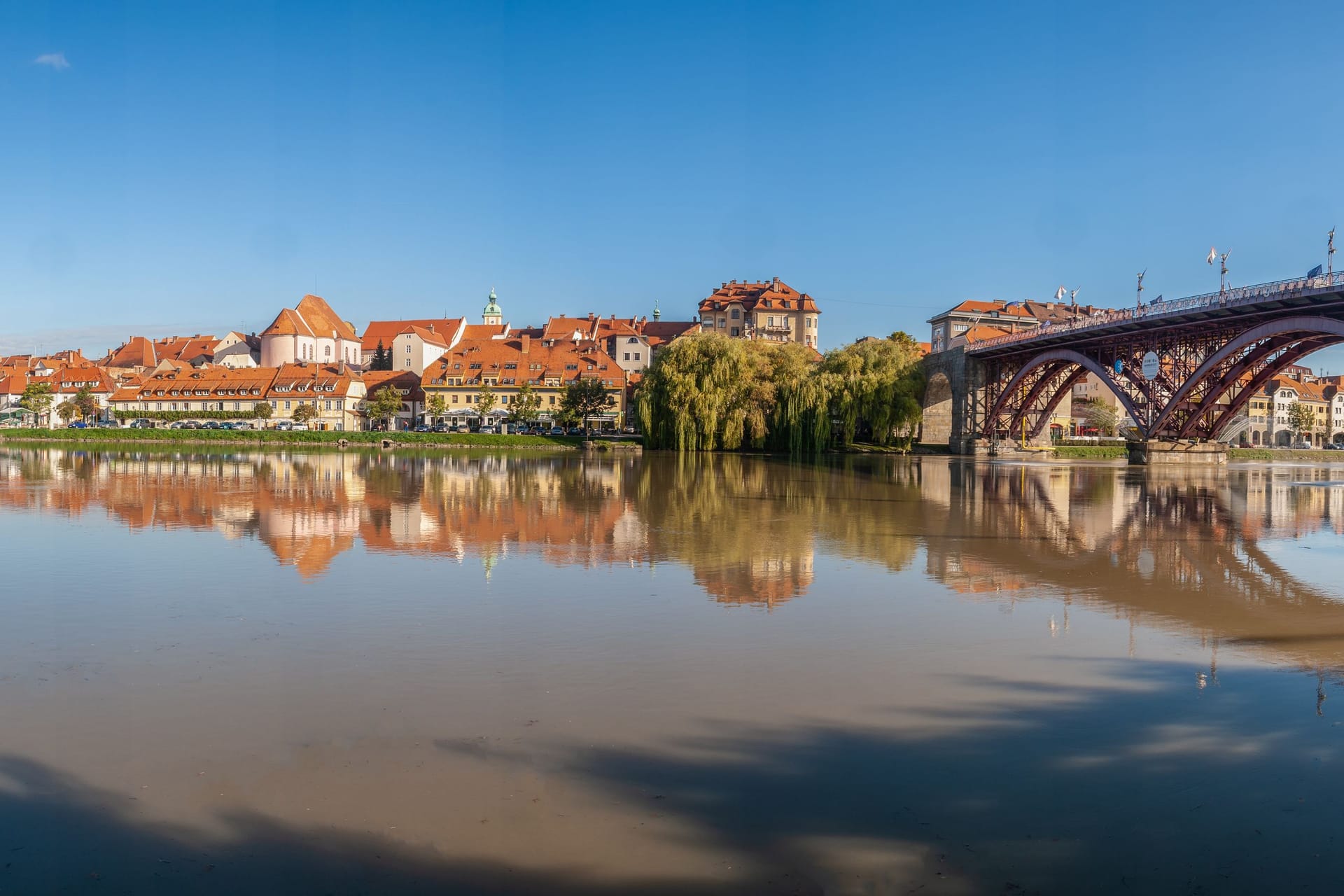 Blick auf die Stadt Maribor und den Fluss Drau mit einer Brücke, die über den Fluss führt: Hier lässt sich Traumurlaub machen.