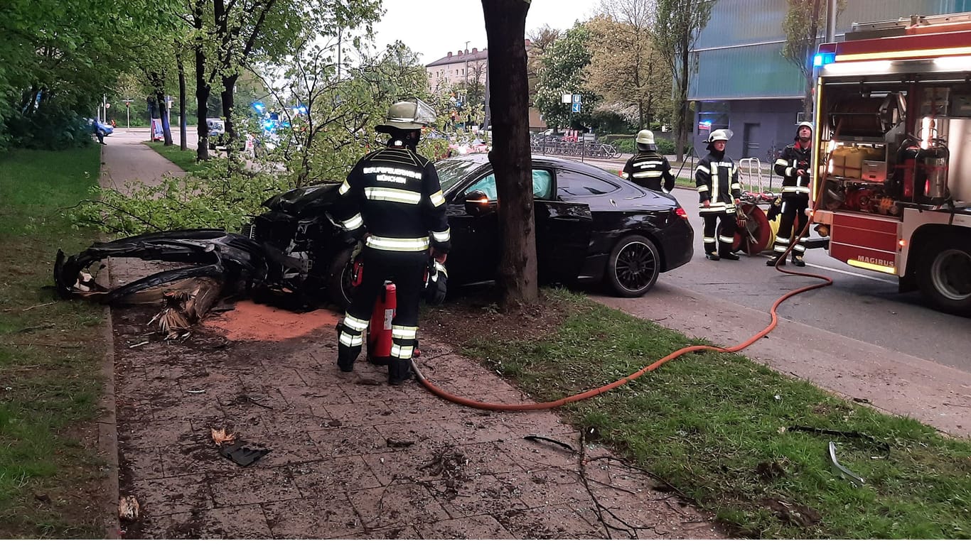Feuerwehrleute begutachten das demolierte Fahrzeug. Der Mercedes war zuvor gegen einen Baum geprallt.