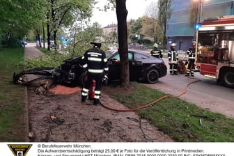 Feuerwehrleute begutachten das demolierte Fahrzeug. Der Mercedes war zuvor gegen einen Baum geprallt.