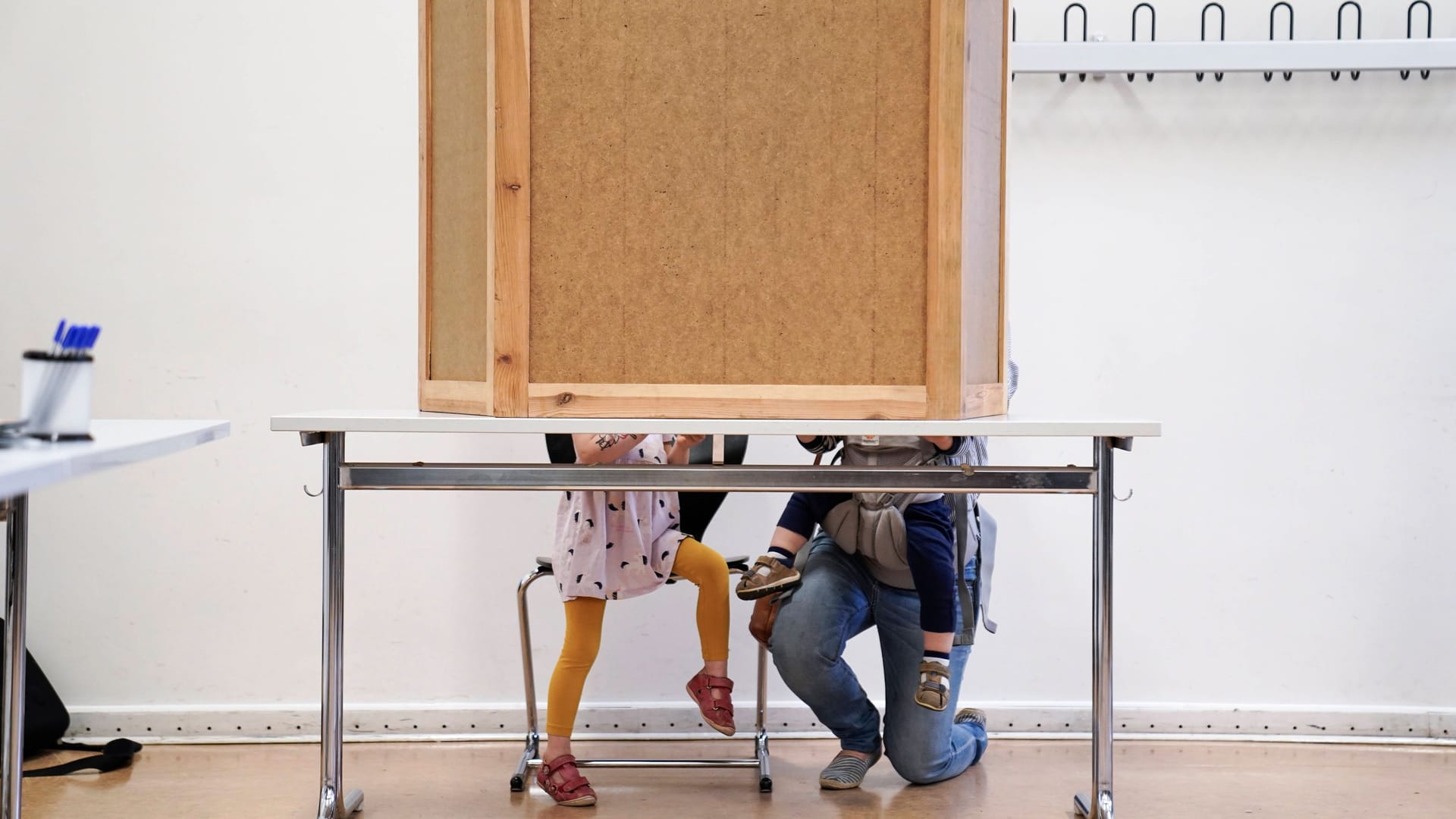 Mutter mit Kindern in Wahlurne (Symbolbild): Ab der kommenden Wahl 2026 sollen 16-Jährige mitentscheiden dürfen.