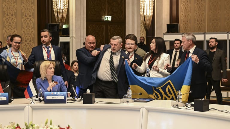 Während der Rede von Olga Timofeeva (links) entfalten ukrainische Delegierte bei der Sitzung der Parlamentarier der Schwarzmeer-Wirtschaftskonferenz eine ukrainische Flagge.