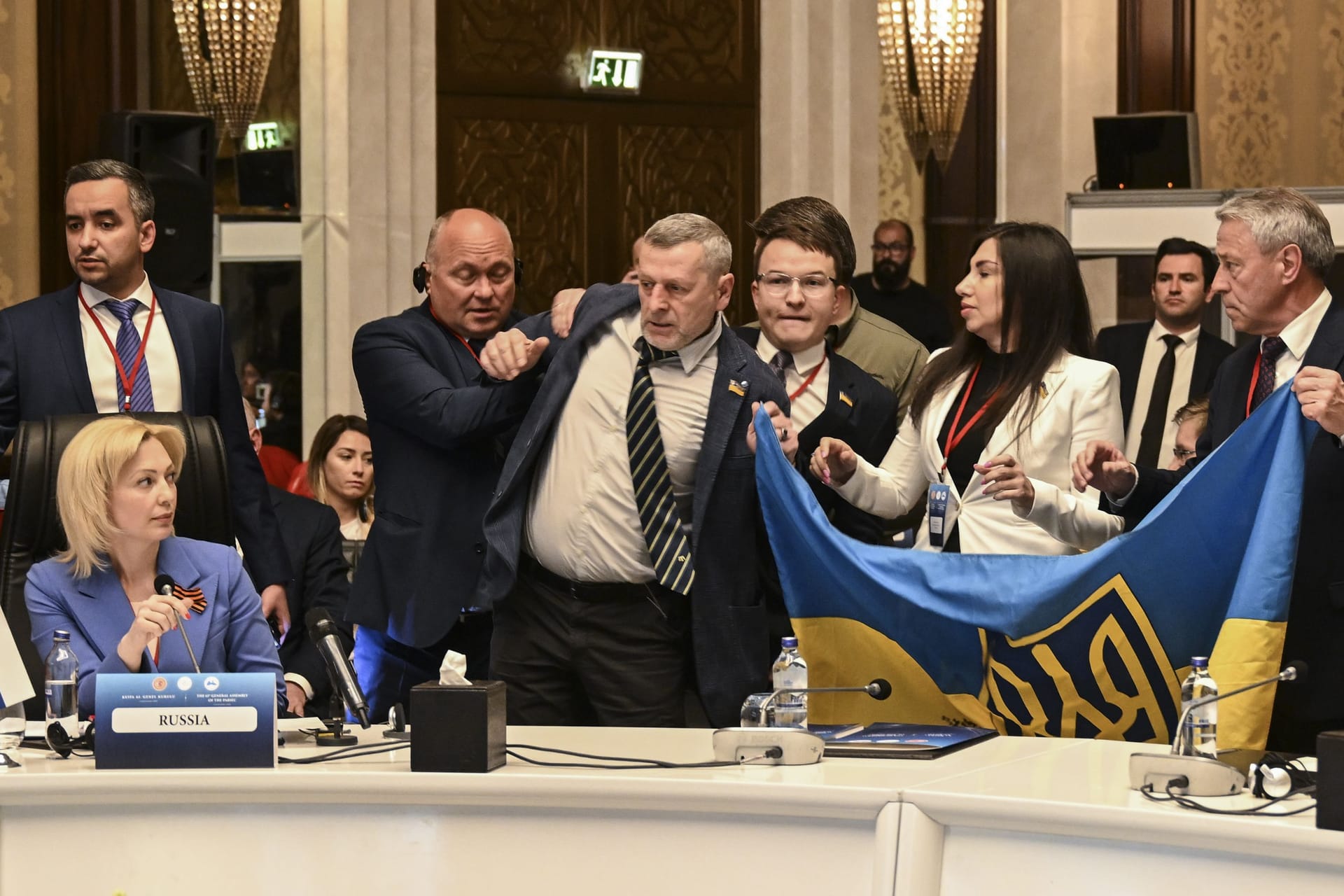 Während der Rede von Olga Timofeeva (links) entfalten ukrainische Delegierte bei der Sitzung der Parlamentarier der Schwarzmeer-Wirtschaftskonferenz eine ukrainische Flagge.