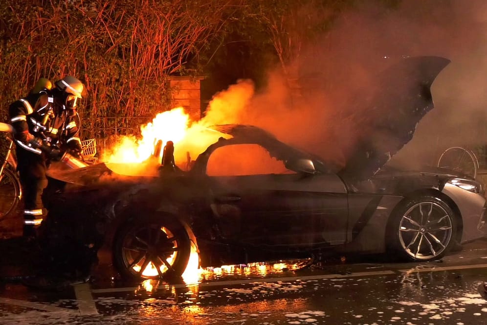 Ein Feuerwehrmann versucht das Feuer zu löschen: An dem BMW entstand Totalschaden.