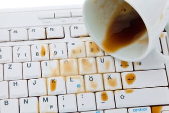 Verschütteter Kaffee beschädigt eine Tastatur: Eine Haftpflichtversicherung kann Sie vor hohen Kosten bewahren.