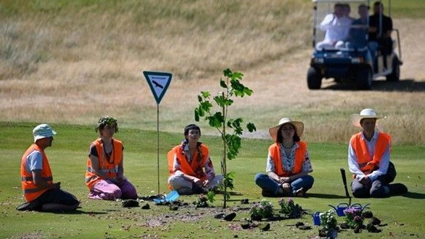 Aktivisten der "Letzten Generation" sitzen auf dem Golfplatz Budersand in Hörnum: Sie pflanzten mehrere Blumen.