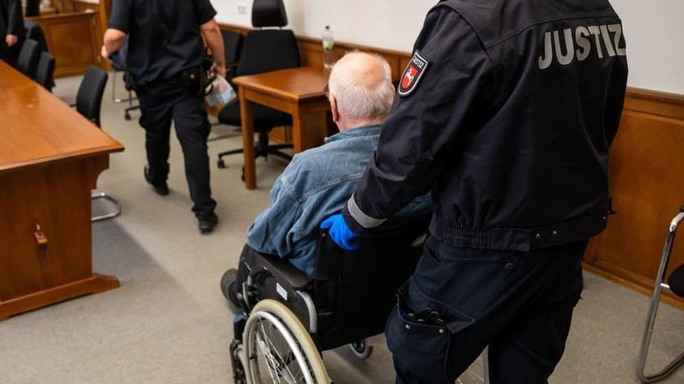 Der Angeklagte wird im Rollstuhl in den Saal des Landgerichts geschoben.
