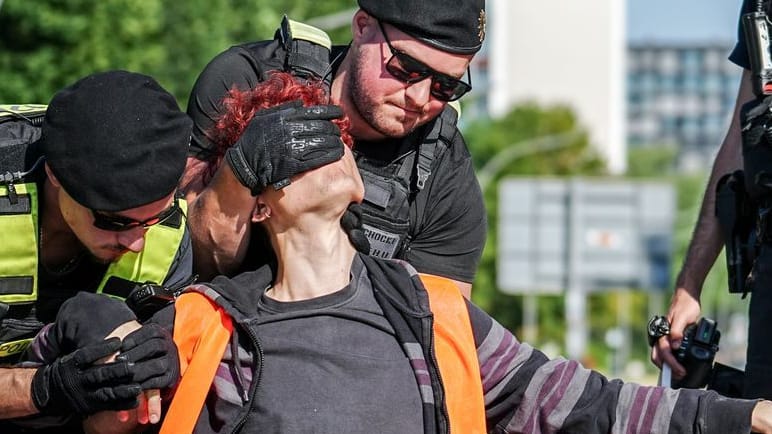 Die "Letzte Generation" auf der Straße: Aktivisten werden bei einer Blockadeaktion am Großen Stern an der Siegessäule in Berlin von der Straße entfernt.