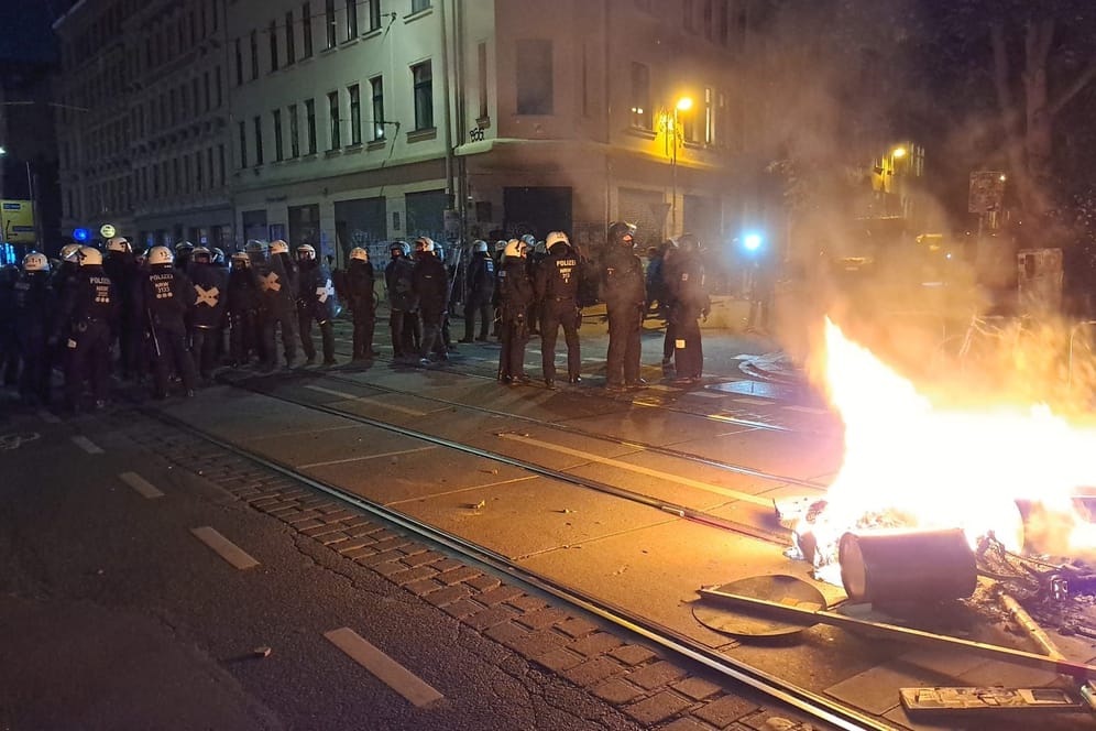 Polizisten stehen vor brennenden Barrikaden in Connewitz. Am Abend flammten die Proteste wieder auf.