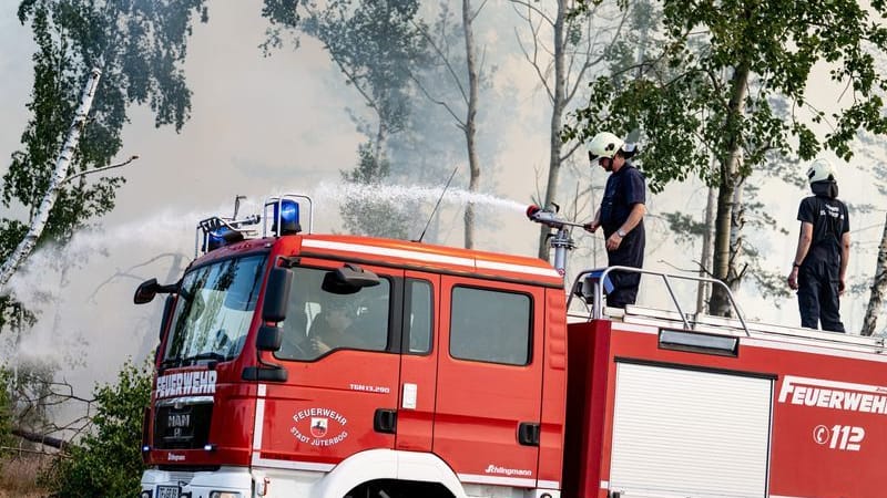 Einsatzkräfte der Feuerwehr bekämpfen in einem Waldstück nahe Jüterbog das Feuer.