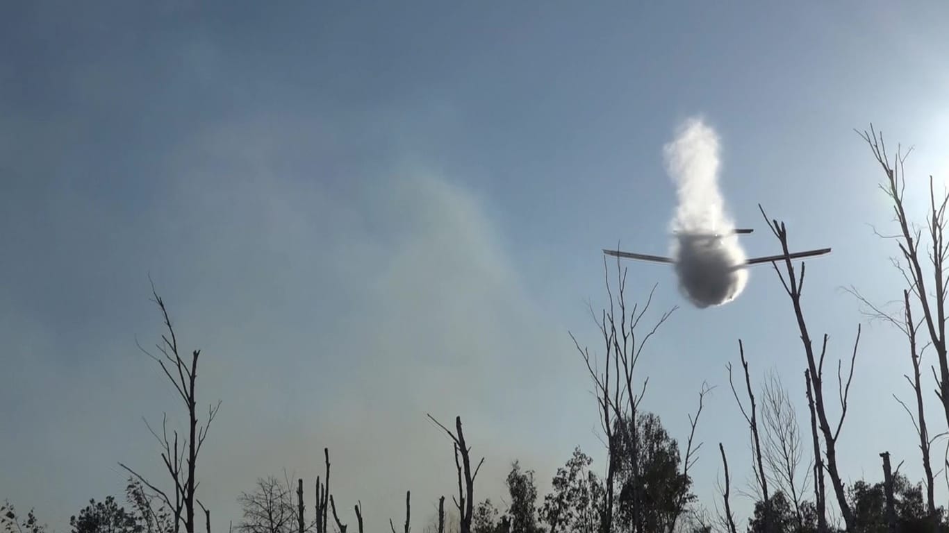 Löschflugzeug wirft Wasser über dem Waldbrand ab: Die Löschung gestaltet sich als schwierig.