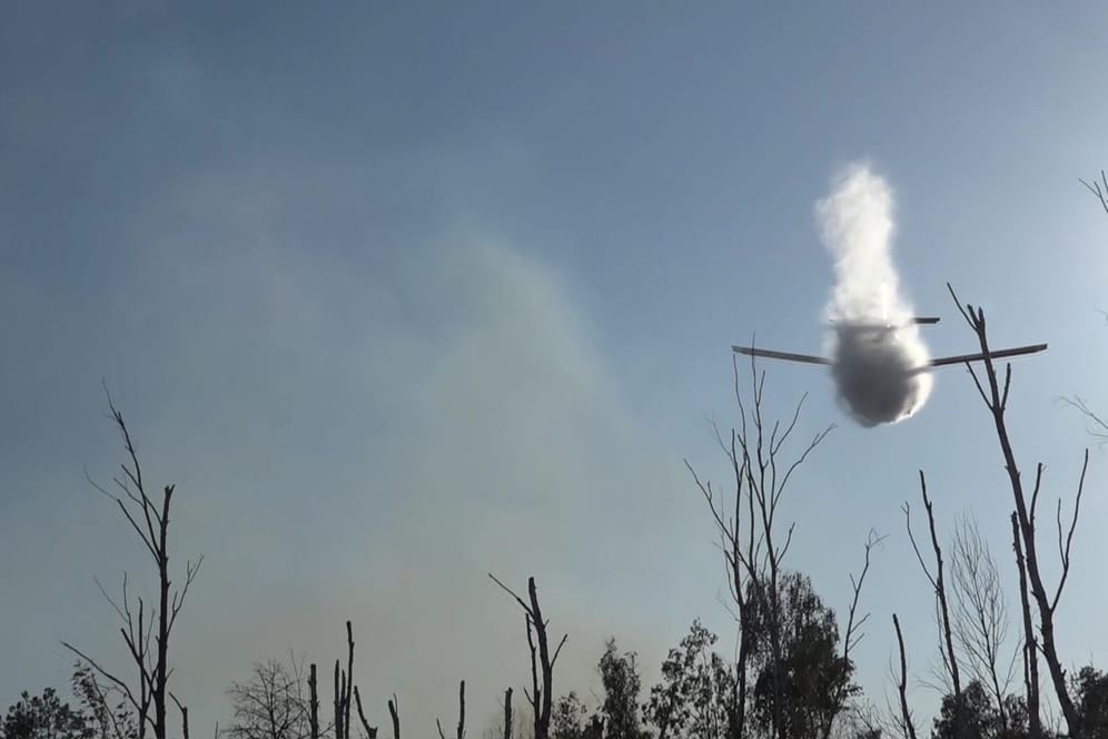 Löschflugzeug wirft Wasser über dem Waldbrand ab: Die Löschung gestaltet sich als schwierig.