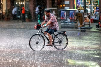 Ein Radfahrer im Regen (Archivbild): In Berlin und Brandenburg kühlt es in den kommenden Tagen ab.