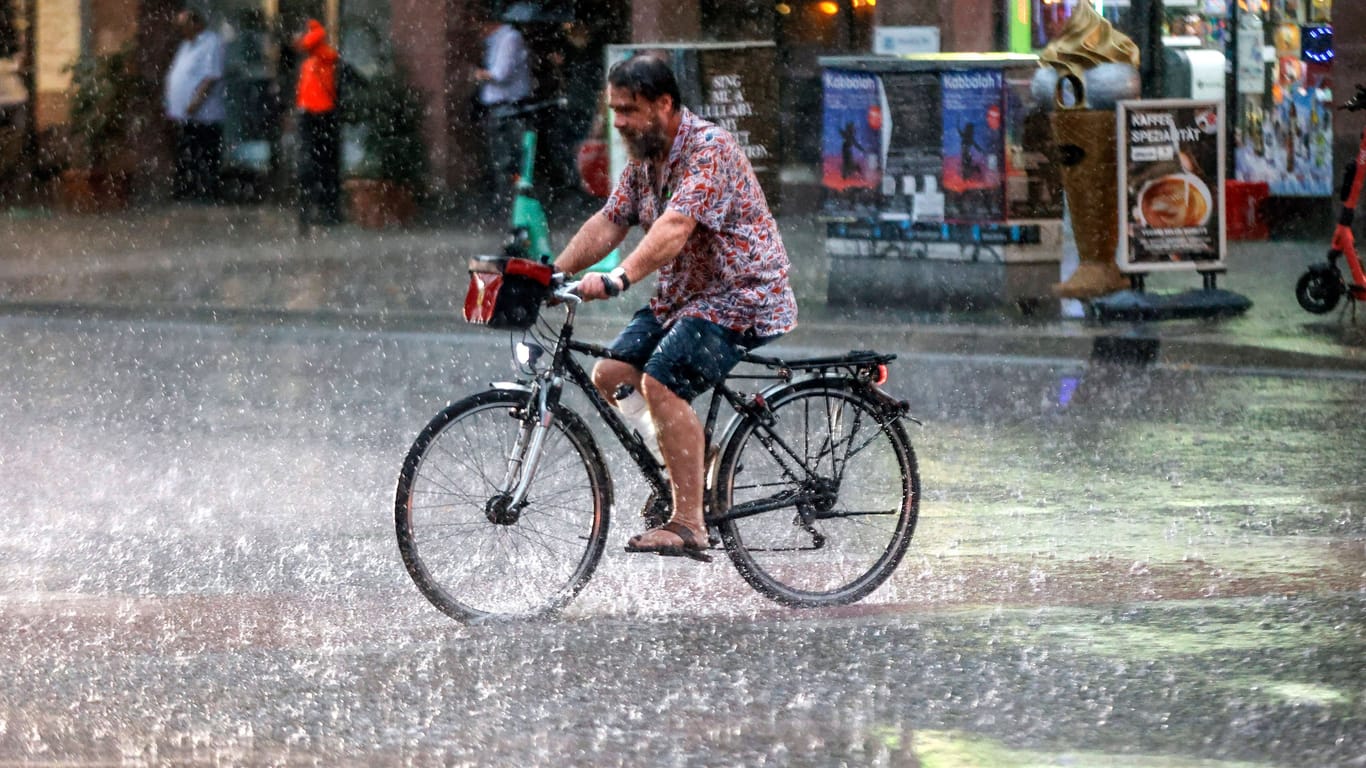 Ein Radfahrer im Regen (Archivbild): In Berlin und Brandenburg kühlt es in den kommenden Tagen ab.